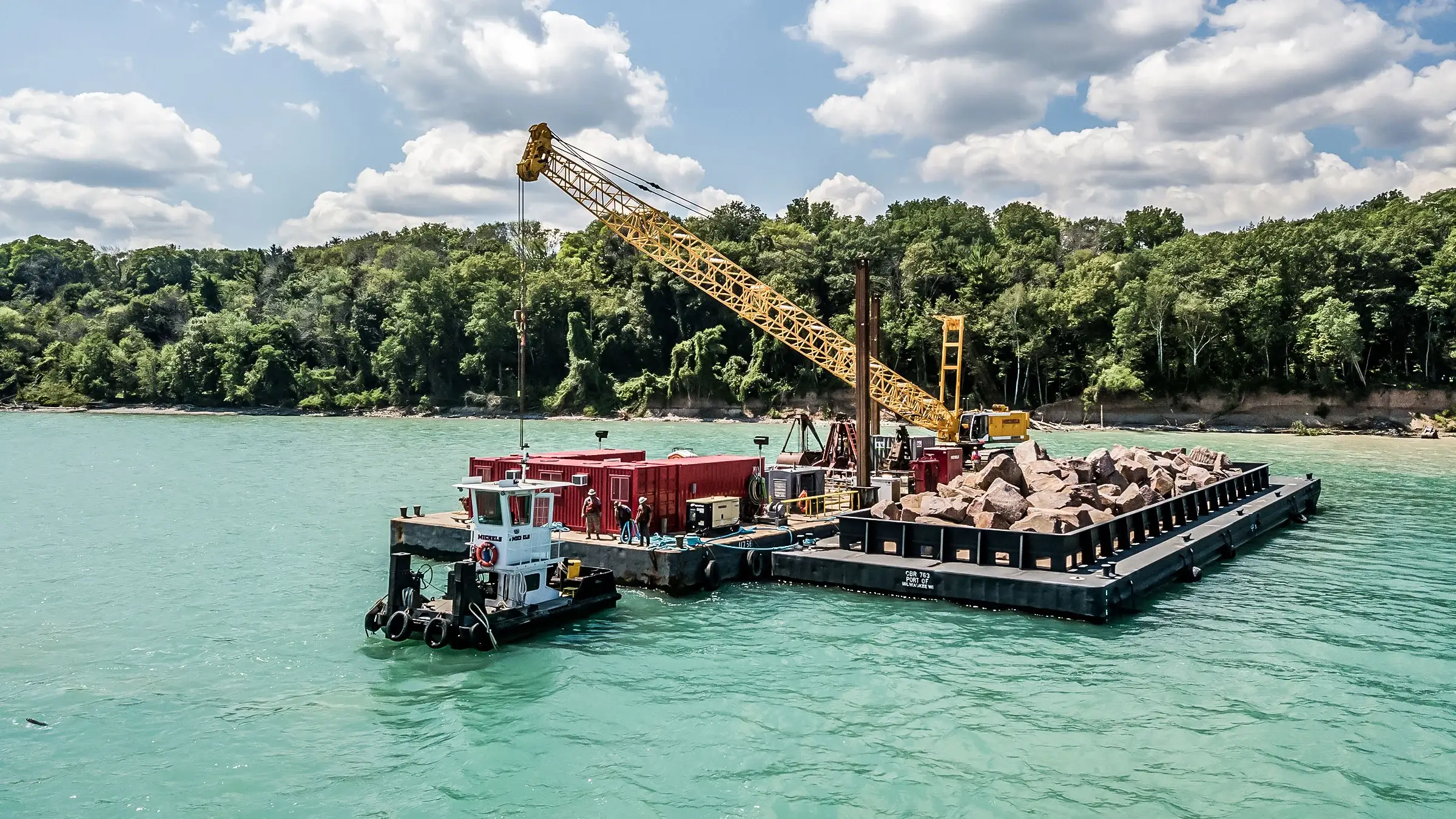 A crane lifts heavy aggregates off-shore from a barge in Lake Michigan